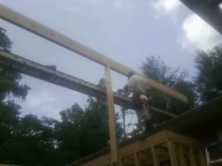 Carpenter setting a ridge beam over a new addition frame — Ice Dam Removal by Roofing Brothers in Cut Off