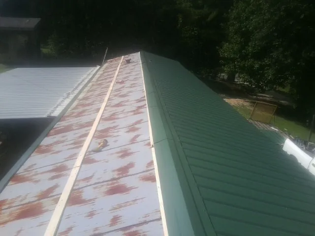 Old rusted panels beside newly installed green metal roofing — Wind Damage Roof Repair by Roofing Brothers in Cut Off