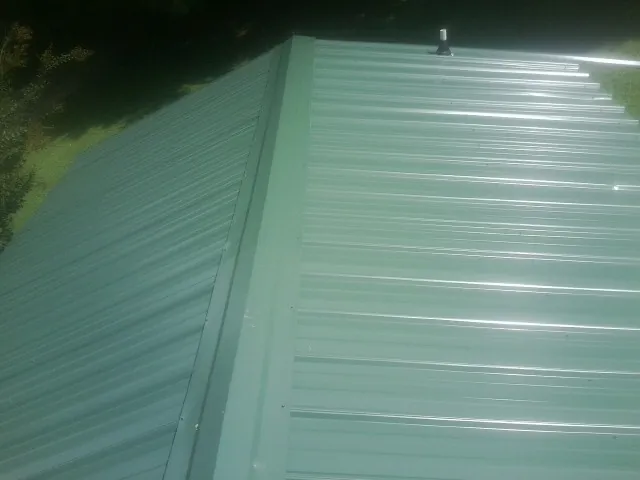 New green metal panels meeting at the ridge of a roof — Flat Roof Repair work by our crew in Cut Off